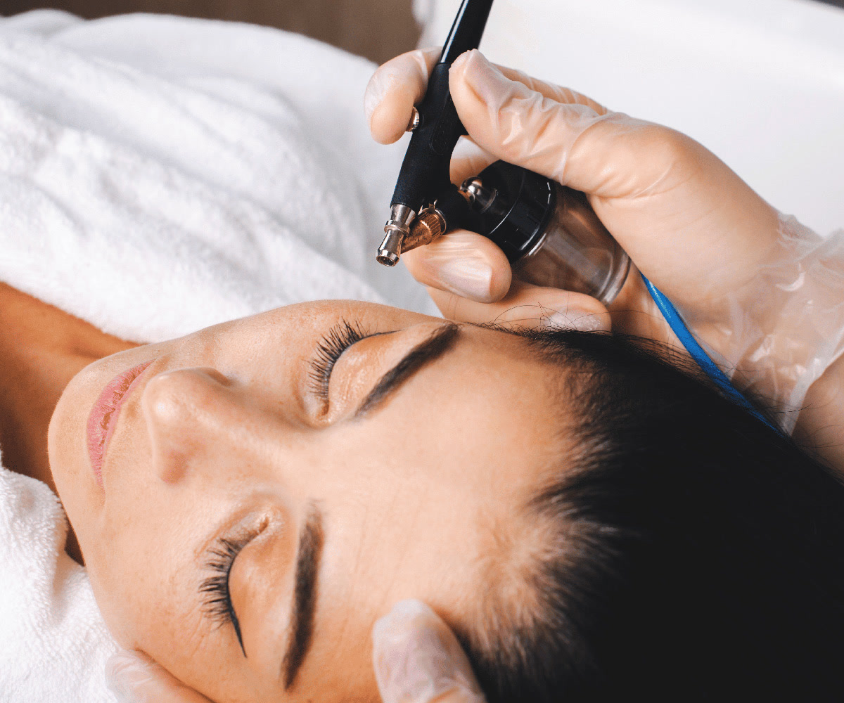 Practitioner applying a serum pen device to a woman's forehead